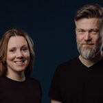 Norbakken and Nystabakk, a woman and bearded man in black shirts, posing against a dark blue background, 2025.