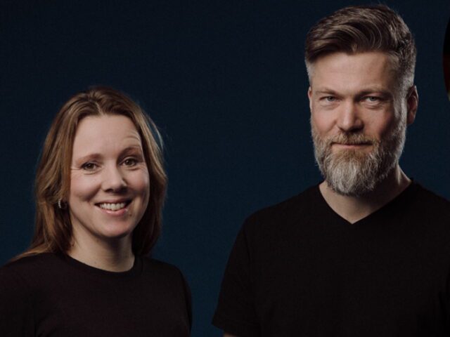 Norbakken and Nystabakk, a woman and bearded man in black shirts, posing against a dark blue background, 2025.